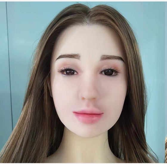 A silicone head doll with human hair, posed in a standing position against a white background. The doll has a realistic appearance, resembling a young woman, with a delicate build and natural curves.