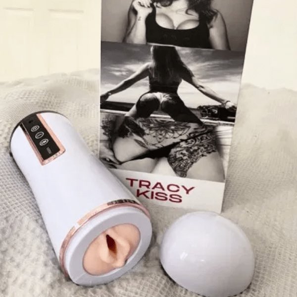 A sleek grey and pink Tracy Kiss Finisher placed next to its packaging. The toy has an ergonomic design with a button control panel on the base and a realistic appearance.